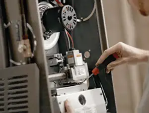 Furnace repair technician inspecting internal components and wiring in Baltimore, MD