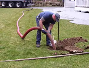 Septic pumping technician servicing a residential septic tank with a vacuum hose in Baltimore, MD