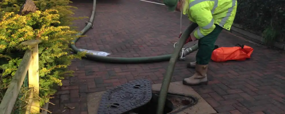 Septic tank cleaning technician servicing a septic tank with a vacuum hose in Baltimore, MD