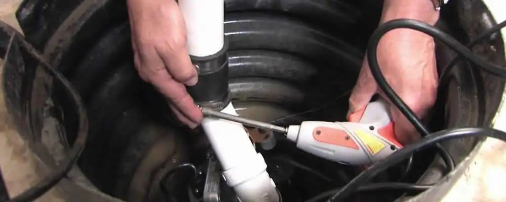Sump pump installation technician connecting PVC discharge piping in Baltimore, MD